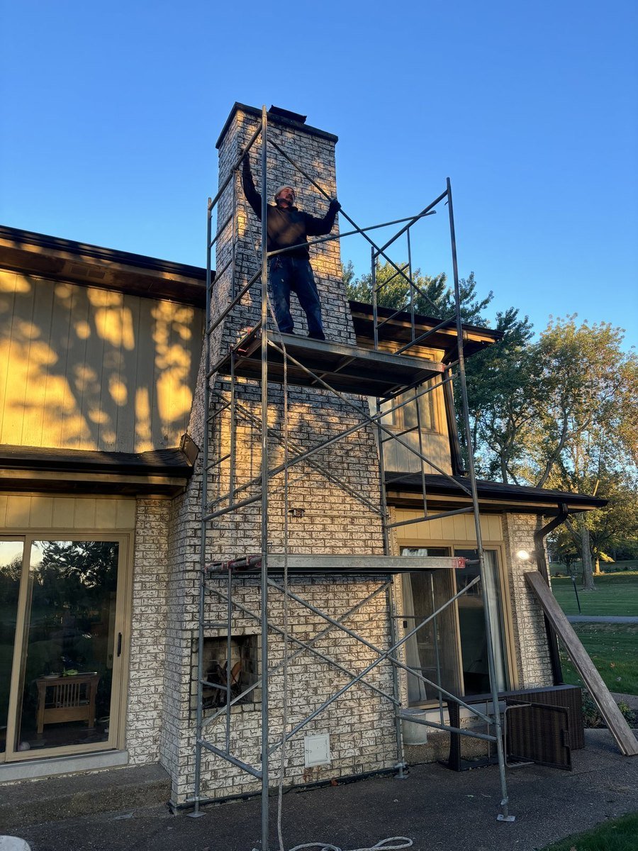 Scaffolded chimney restoration at dusk