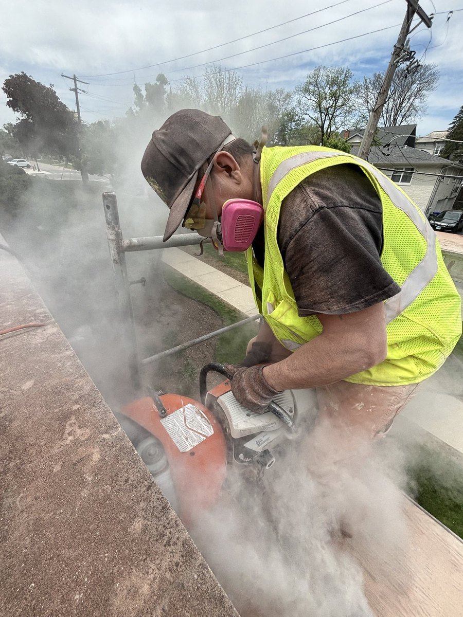 Mason grinding out mortar joints in protective gear